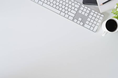 Flat lay top view office desk. Workspace with keyboard and office supplies with coffee on white background.の写真素材
