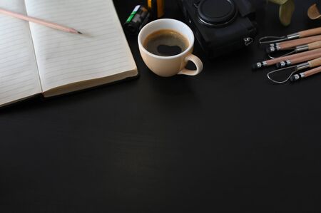 Creative workplace camera, coffee and note paper on black table with selective focus.の写真素材
