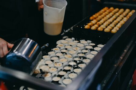 Closeup hand making takoyaki. Takoyaki is a ball Japanese snack popular snack.の写真素材
