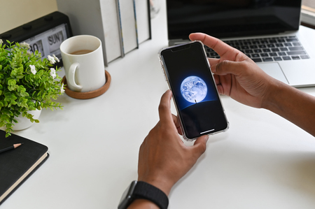 CHIANGMAI, THAILAND - MARCH 30, 2019: A man holds Apple iPhone XS Max with wechat app on the screen on office desk/のeditorial素材