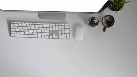 Top view Workspace with blank screen computer, pencil, plant pot and coffee cup on white desk.の写真素材