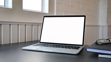 Laptop empty screen with glasses and notebook on black table.の写真素材