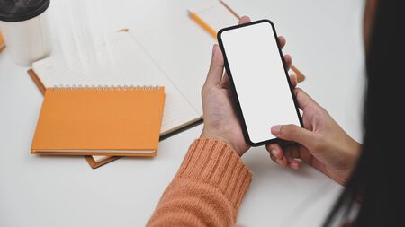 Creative woman using smartphone with empty screen on work desk.の写真素材