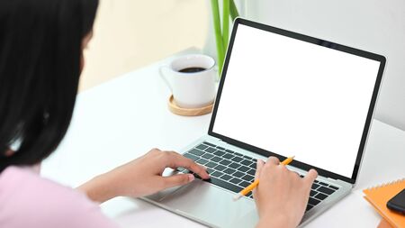 Woman using laptop computer with blank screen in creative workspace.の写真素材