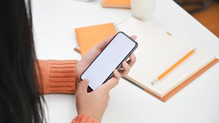 Young woman using mockup mobile phone on table.の写真素材