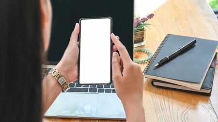 Closeup woman holding smartphone with empty screen on office desk.の写真素材
