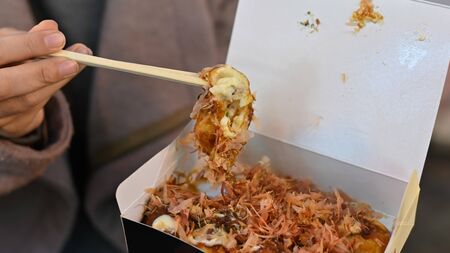 Closeup box of takoyaki ready to eat on woman hands.