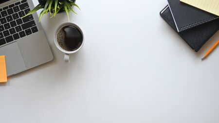 Tabletop office desk with laptop, notebook, pencil, plant with white table.の写真素材