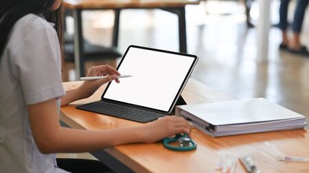 Behind shot woman doctor using isolated white screen of tablet and stylus.の写真素材