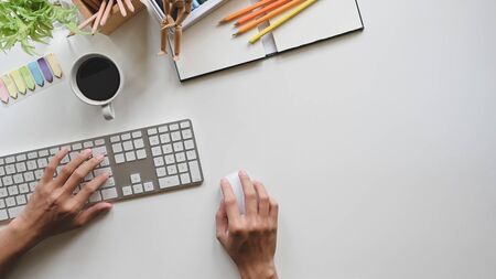 Male hands working on computer on white copy space office desk background.