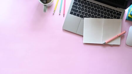 Pastel top view workspace with laptop, notebook, pencil and coffee cup on pink office desk.の写真素材