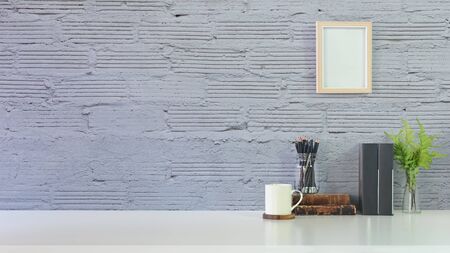 Workspace with pencil, books, plant on vase, coffee and photo frame decoration with concrete wall.の写真素材