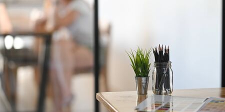 Pencil on glass and plant pot on wood table front of meeting room.の写真素材