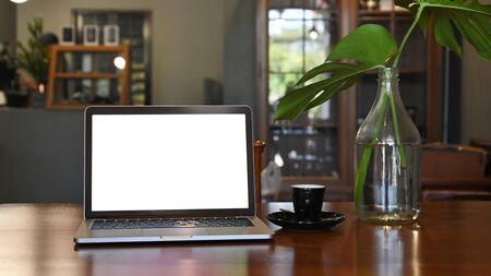 Laptop computer mockup empty screen on wood table in coffee cafe.の写真素材