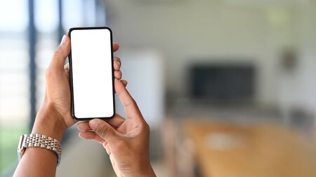 Smartphone on hands with empty screen and meeting room blur background.の写真素材