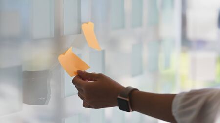 Closeup woman sticking note on board with reminder memo.の写真素材