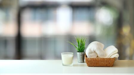 Towel is putting on the 
wicker basket, Candle and potted plant on the white table. Massage therapy concept.の写真素材