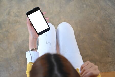 Top view photo of beautiful woman sitting and listening the music from white blank screen smartphone.の写真素材