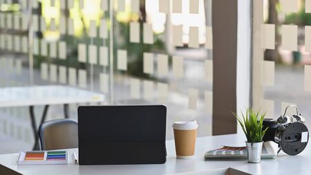 Back view cropped shot of Laptop, coffee cup, alarm clock, potted plant, color, color guide on the working desk,の写真素材