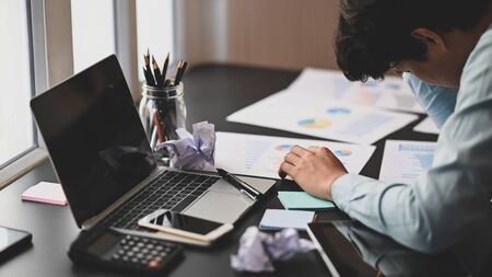 Photo of young businessman hand on his head at the working desk after feeling frustrated exhausted from work. Frustrated/Stress from work.の写真素材