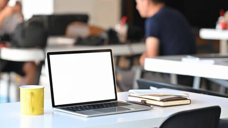 Photo of modern laptop with white blank screen display and office equipment are putting on the white...