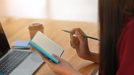 Side shot of young writer woman is writing/giving concentrate on notebook while sitting at the...