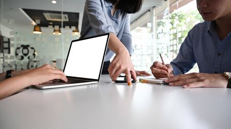 Cropped image of secretary woman typing on white blank screen laptop while her leader are discussing/talking about business plan at the modern meeting table. Space screen for advertise concept.の写真素材