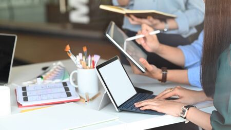Closeup young graphic designer team planning/meeting/discussing about them Business growth guidelines at the modern meeting table with computer tablet and notebook. Collaboration in office concept.の写真素材