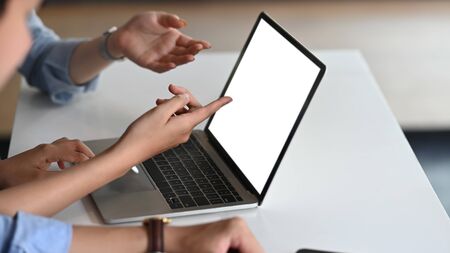 Cropped image of business people discussing/talking about them business result that showing in a laptop at the modern meeting table. Computer laptop with white blank screen for advertise concept.の写真素材