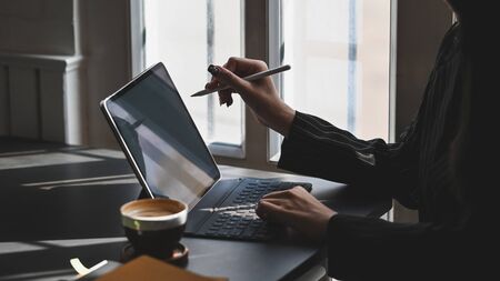 Young executive woman pointing electric pen to the computer tablet while contemplate about work at the modern working desk with luxury office room as background.の写真素材