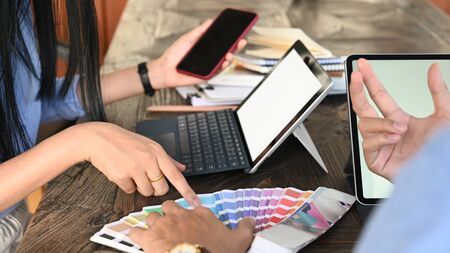 Cropped image of graphic designer team discussing about color for their new project at the wooden...