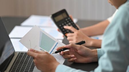 Cropped image of accountant people discussing/checking about their business selling result by using a graphic chart and calculator at the modern meeting table with comfortable.の写真素材