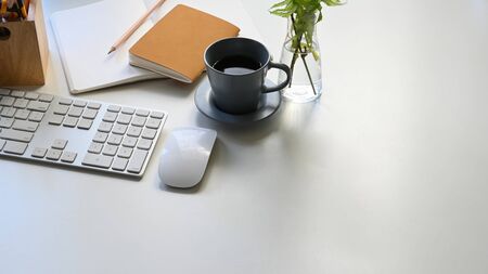 Photo of Coffee cup, keyboard, mouse, notes, pencil and potted plant putting together on modern...