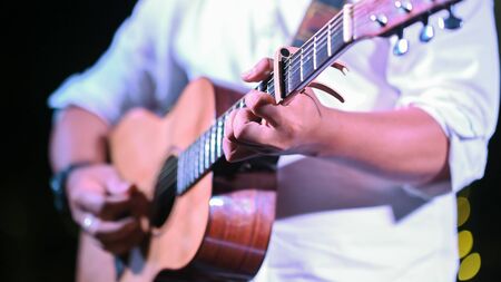 Cropped image of night musician working as guitarist while standing and playing his classical guitar...