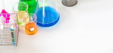Photo of Chemistry glassware with colored liquid putting together on white modern desk in orderly laboratory. Orderly scientific working table concept.の写真素材