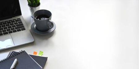 Photo of computer laptop, coffee cup, notebook, diary, pen, potted plant putting on white working...