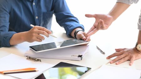 Cropped image of graphic designer team working/meeting by computer tablet while sitting/standing at...