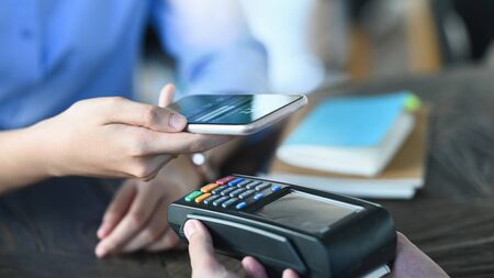 Cropped image of smart man's hands holding a smartphone and doing a payment by using a NFC...