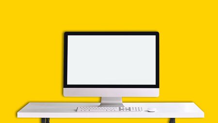 Photo of Computer monitor with white blank screen putting on white working desk on isolated yellow background.の写真素材