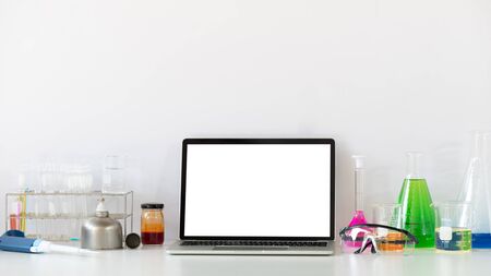 Photo of Scientific experiments equipment putting on white working desk with white blank screen...