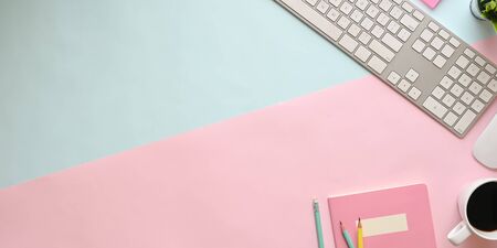Top view image of pastel color working table with office equipment putting on it. Flat lay keyboard, wireless mouse, coffee cup, notebook, potted plant and pencils. Adorable workplace concept.の写真素材