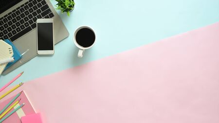 Copy space pastel office desk with laptop, smartphone and office supplies with coffee on top view table.の写真素材