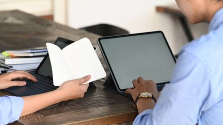 Cropped image of business developer team working with computer laptop and tablet while sitting...
