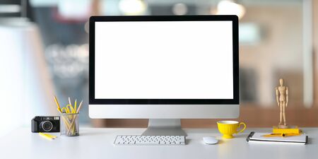 Photo of Computer monitor with white blank screen putting on white working desk and surrounded by...