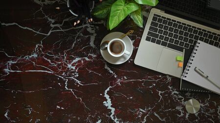 Top view image of computer laptop putting on marble texture table with coffee cup, potted plant, notebook and pen. Modern and luxury workspace concept.の写真素材