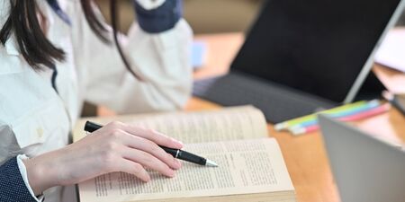 Cropped image of young woman tutoring her lesson while sitting in front her book and computer tablet...