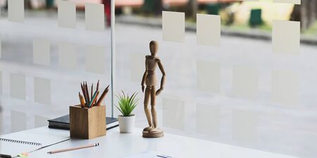 Wooden model putting on creative working desk that surrounded by wooden pencil holder, notebook,...