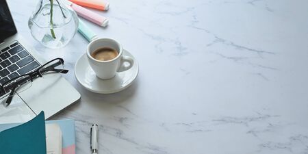 Photo of ceramic coffee cup putting on marble texture desk that surrounded by computer laptop, eye...