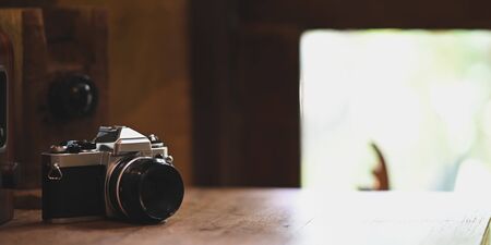 Retro camera putting on wooden table over vintage wooden room as background. Photographer, Photographing and Traveling concept.の写真素材