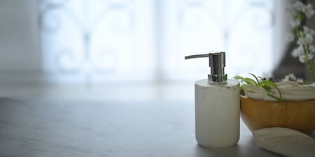Pump dispenser bottle putting on marble texture surrounded by wooden bowl, pine cone, tree branch, napkin and calico. Bathroom and spa equipment concept.の写真素材